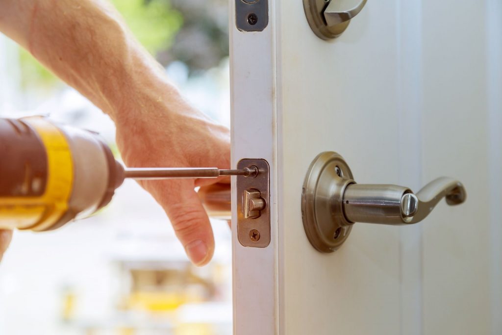 LW Locksmiths Warrington installing a silver lock and handle to a white door.